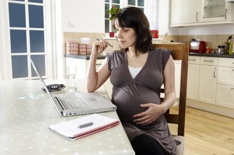 A pregnant woman looking at a laptop
