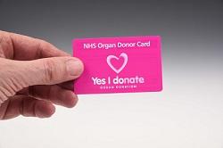 A hand holding an NHS organ donor card